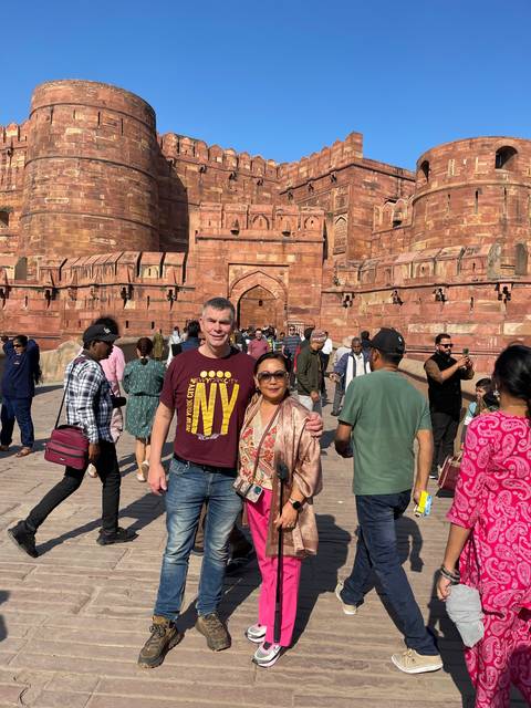       Group posing in front of impressive red stone architecture.
  