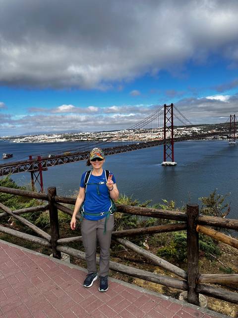 A person standing with a bridge in the background.