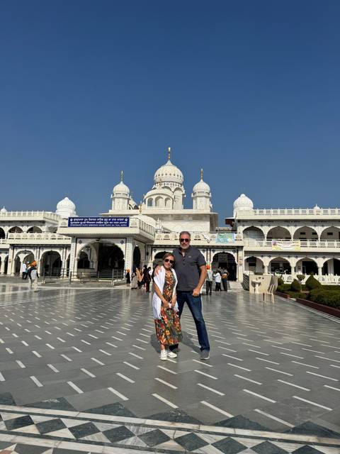       Couple standing in front of a white temple with domes.
  