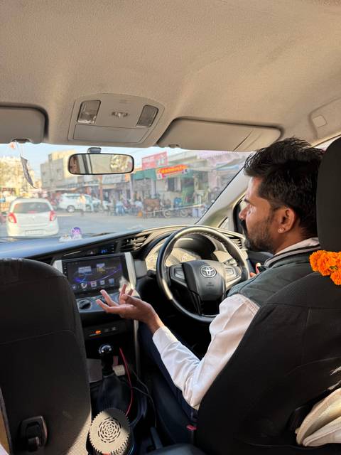       Driver inside a car navigating through a busy street.
  