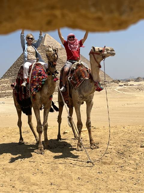       People on camelback in desert landscape
  