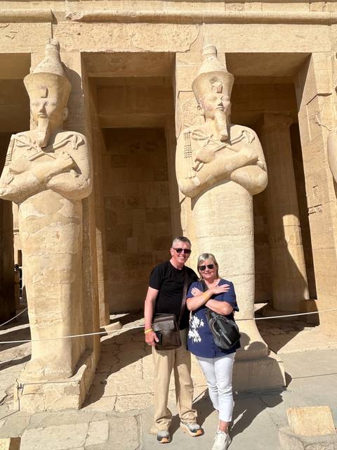       Couple posing in front of ancient statue.
  