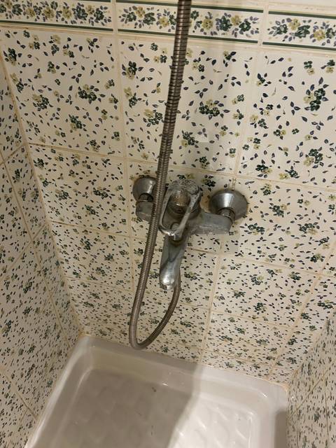       Close-up of a bathtub faucet with floral tiles as background.
  