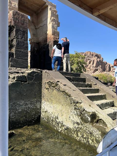 Two people exploring ancient ruins with hieroglyphics.