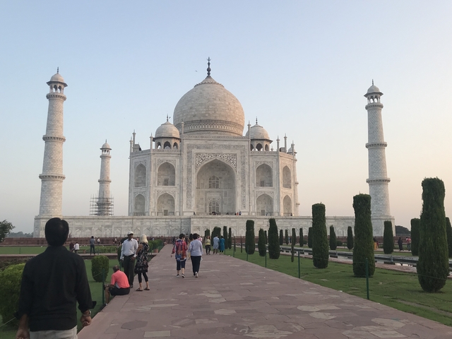      Wide view of the Taj Mahal at sunset with visitors.
  
