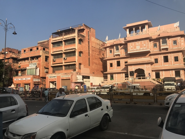       Pink historic buildings with cars and people on the street.
  