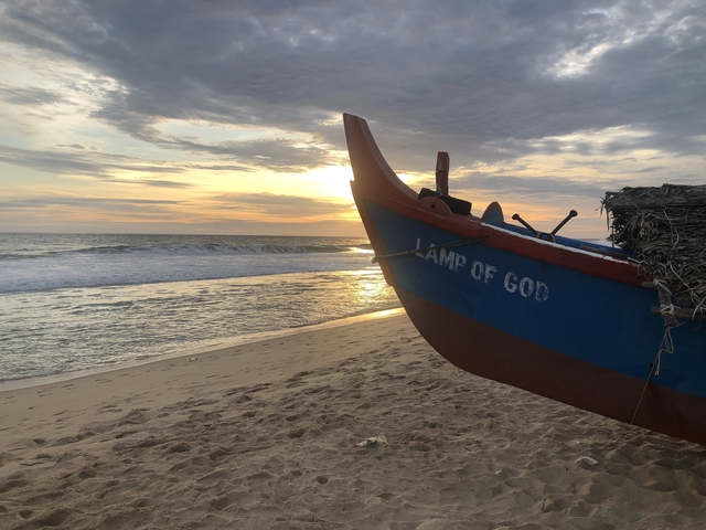 Boat on beach during a sunset with a visible inscription.