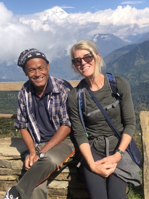 Two people smiling with mountains in the background.