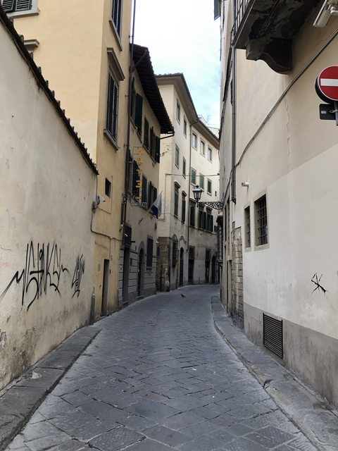       Narrow street with old buildings and graffiti.
  