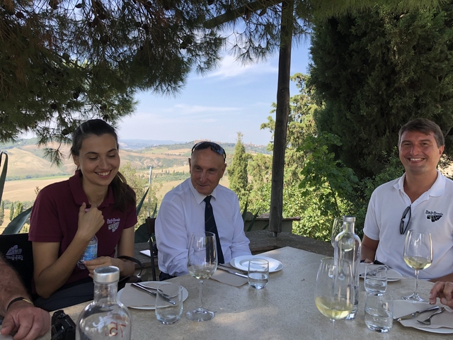       People dining outdoors with a scenic view in the background.
  