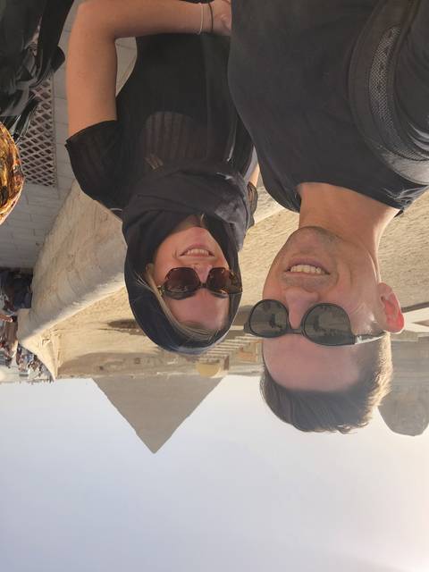 A couple posing with a pyramid in the background.