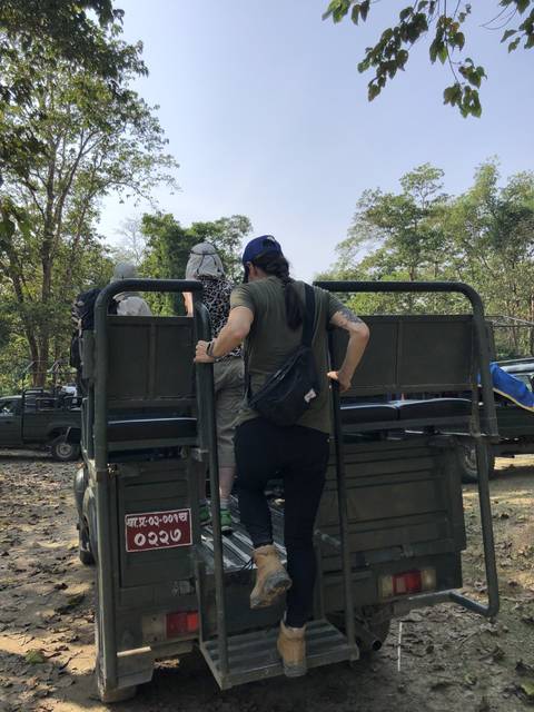 Tourists climbing onto an open vehicle.