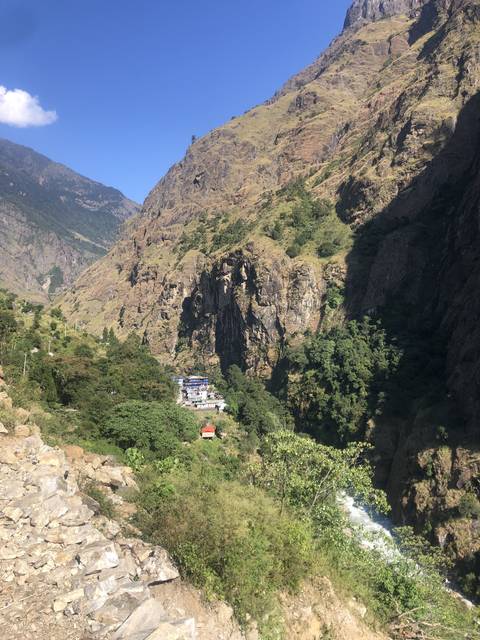       Mountain landscape with a waterfall and buildings surrounded by trees.
  