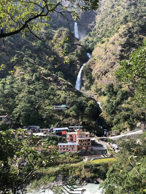       Waterfall and buildings in a mountainous landscape.
  