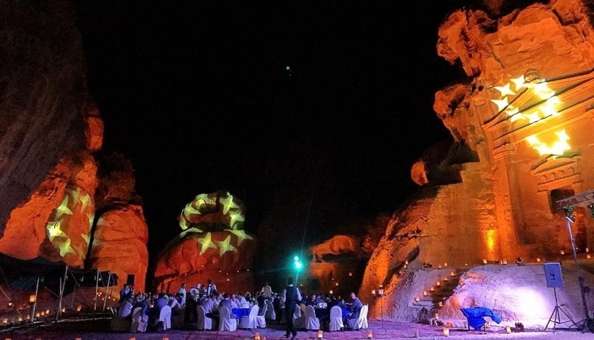       Dinner event with stars projected on rocky outcrops.
  