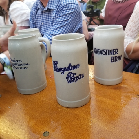 Close-up of beer steins with brewery logos on a table.