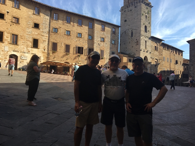       Three men posing in a historic square.
  