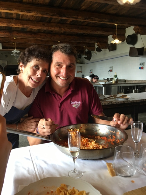       Two people smiling with a pasta dish.
  