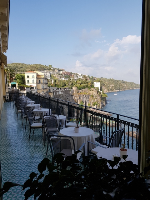       Seaside terrace with outdoor dining tables overlooking cliffs.
  