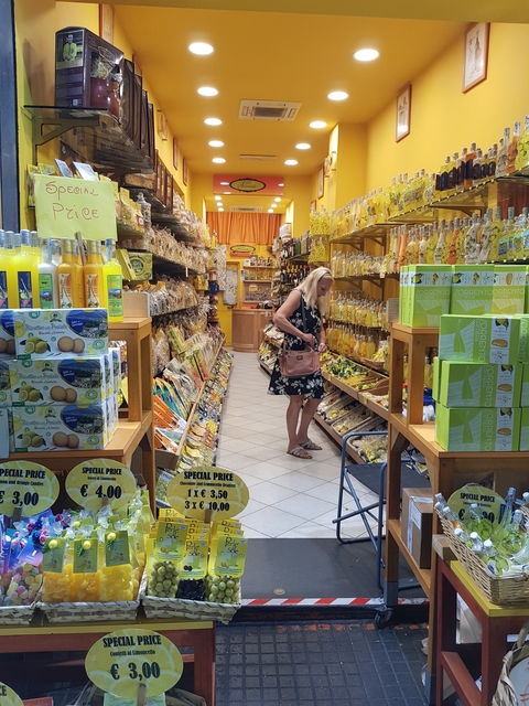       Woman browsing lemon-themed products in a souvenir shop.
  