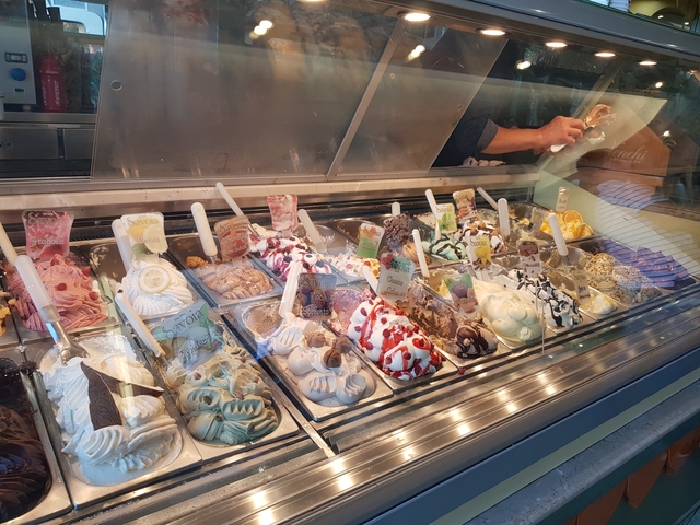       Colorful assortment of gelato displayed in a cafe.
  