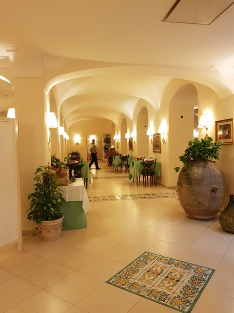       Elegant dining area in a hotel with a man walking by.
  