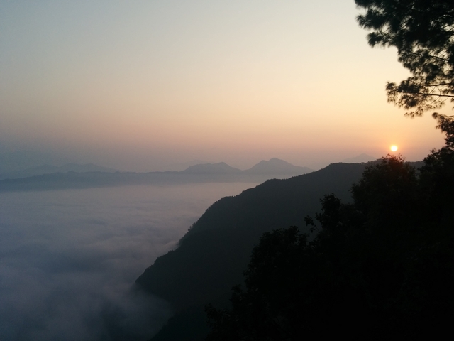 Sunrise over a foggy valley with mountains.