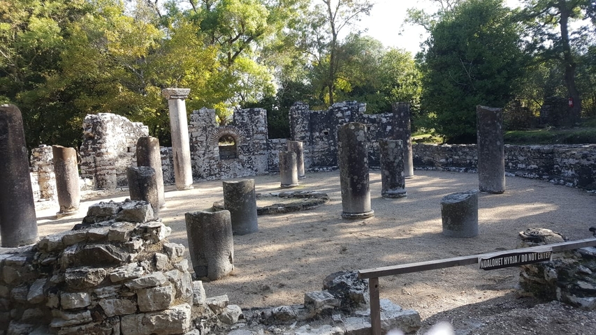 Ancient ruins with columns and trees around.