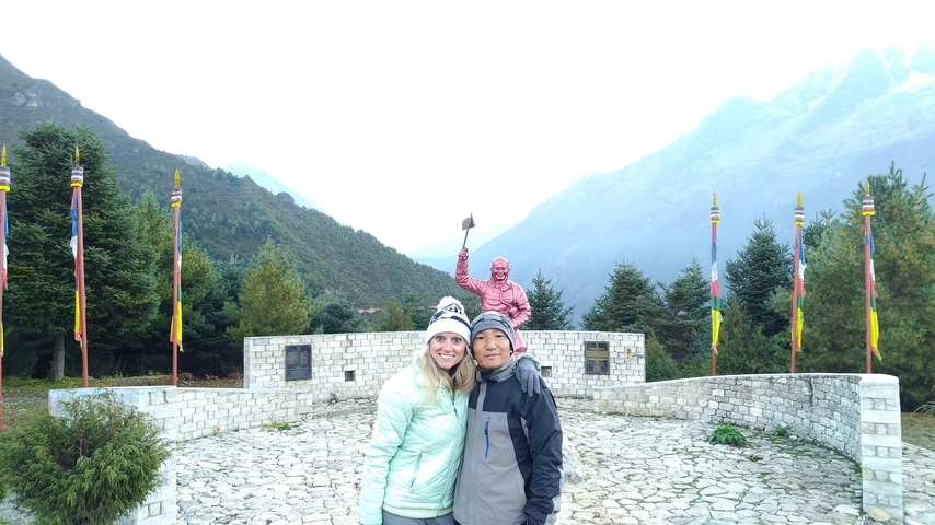 Couple posing in front of a monument with mountains.