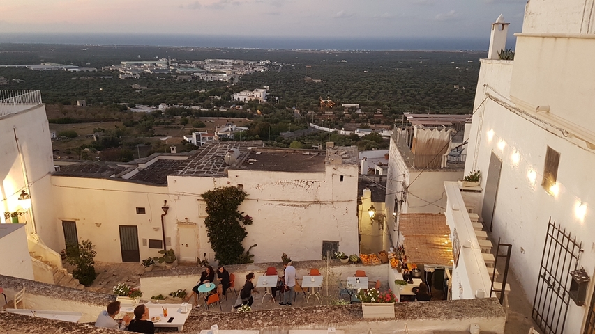       People dining outdoors with city view.
  