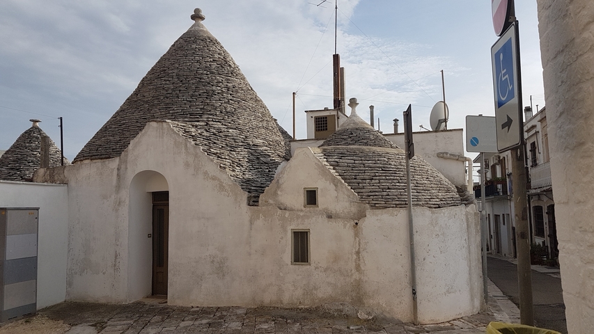 Stone trulli house with a cloudy backdrop.