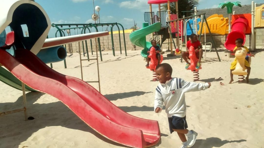       Children playing in a playground with slides.
  