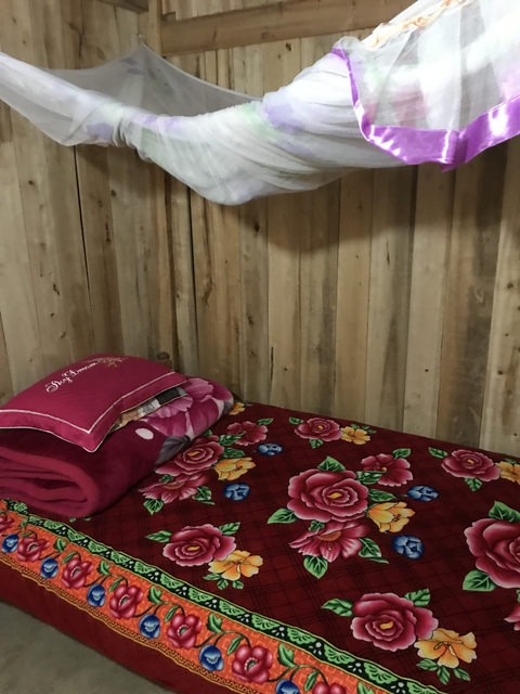Simple room with wooden walls and floral bedding.