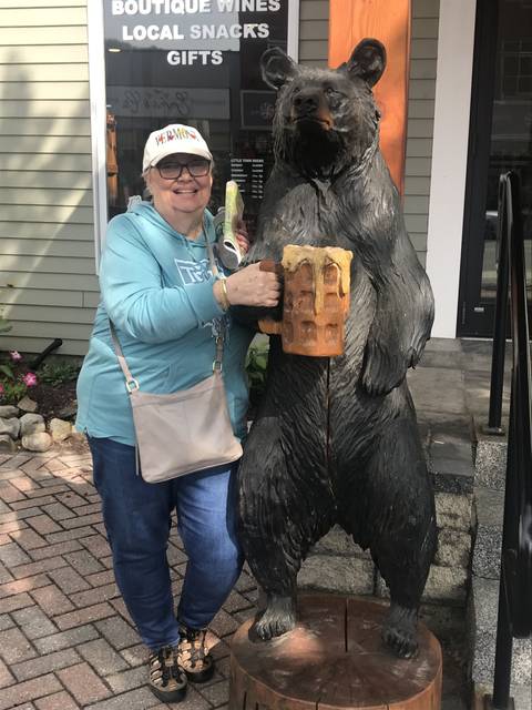      Person posing with a statue of a bear holding a waffle.
  