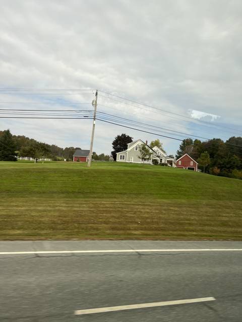 A house with a red building in a grassy area.