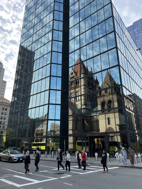       Modern glass building with reflections of another structure.
  
