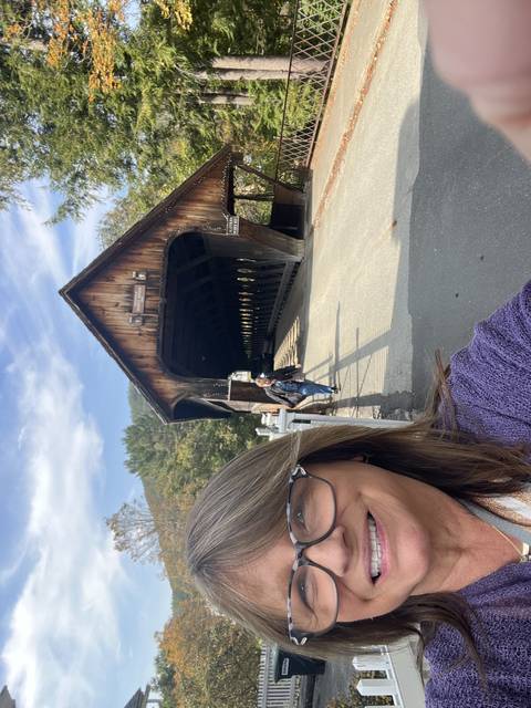       Person smiling with a covered bridge in the background.
  