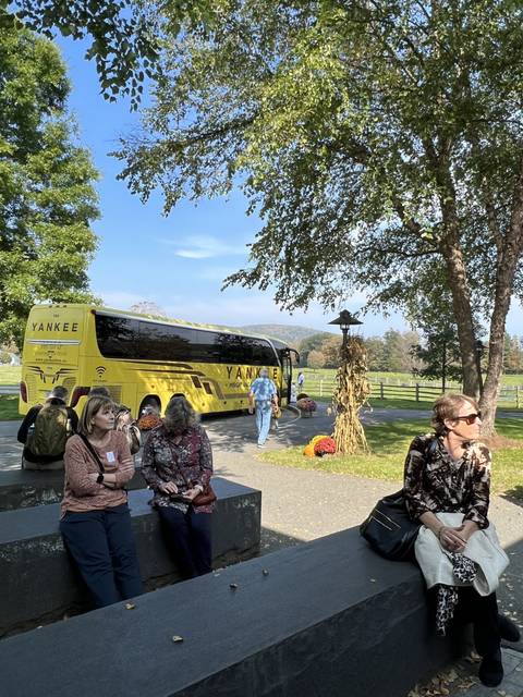 Group of people sitting near a yellow bus.
