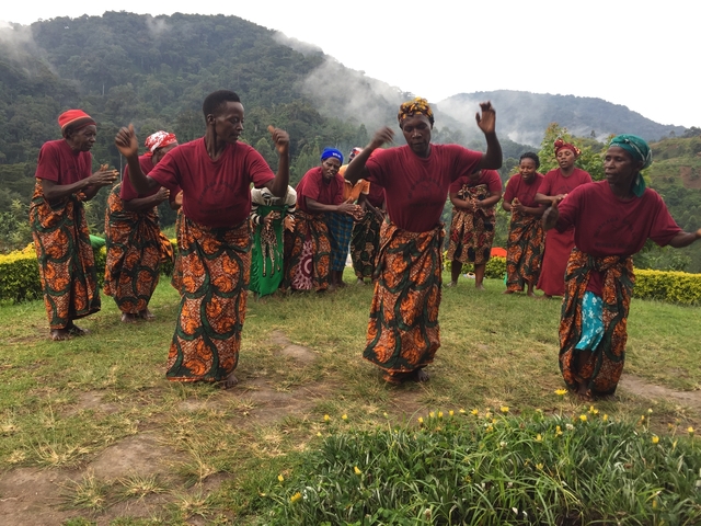       Group of people in traditional attire dancing in a scenic mountain setting.
  