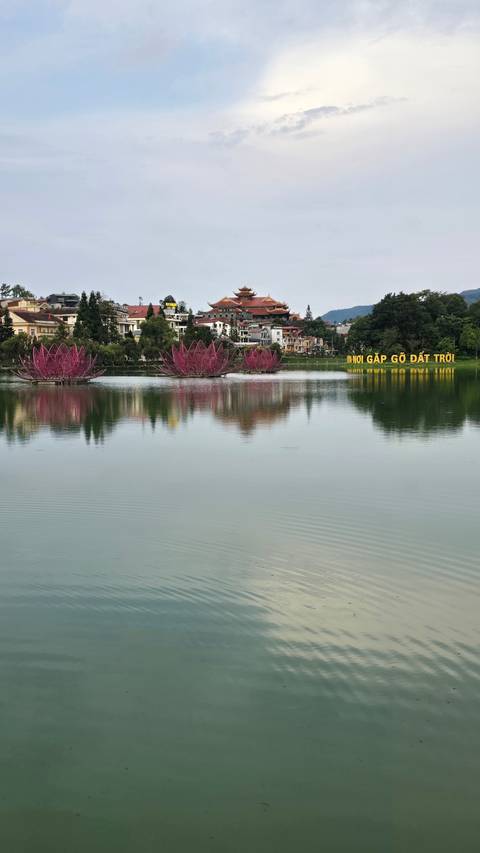       Tranquil lake with buildings and trees reflected in the water
  