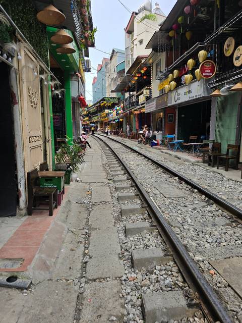       Narrow street with train tracks and colorful buildings
  