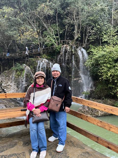       Two people posing near a waterfall.
  