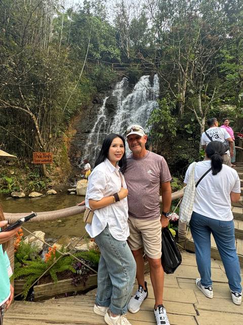       People posing in front of a waterfall and greenery.
  