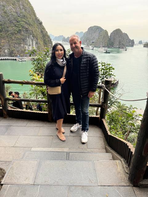       Two people posing with a scenic view of the ocean.
  