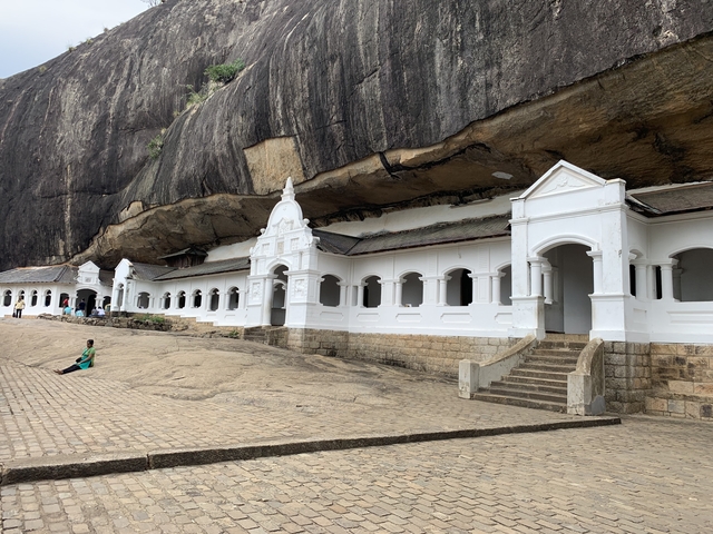 White temple structures built into a rock face.