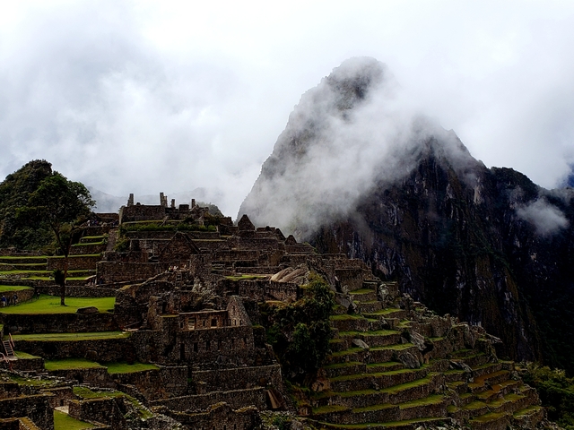 Machu Picchu ruins with misty mountains in the background.