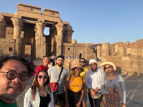       Group of people posing in front of stone ruins.
  