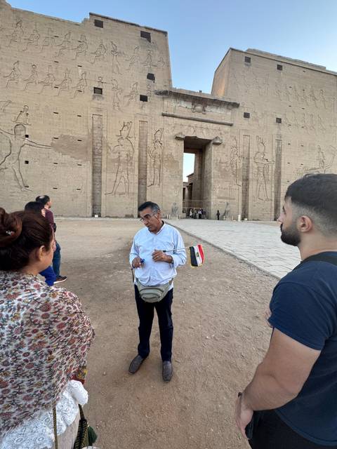      Tour guide speaking to a group in front of an ancient Egyptian structure.
  
