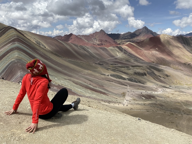 Woman sitting at Rainbow Mountain, Peru.