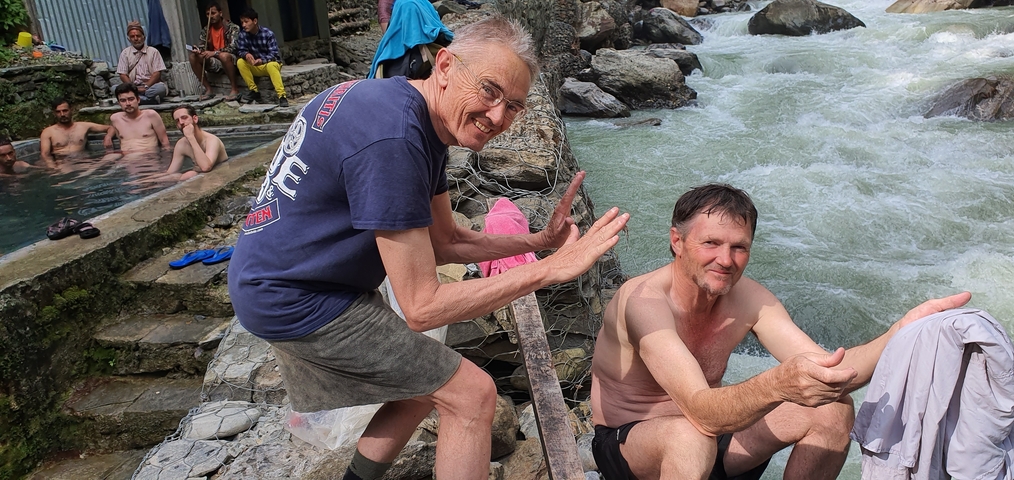 Men enjoying hot springs by a river.